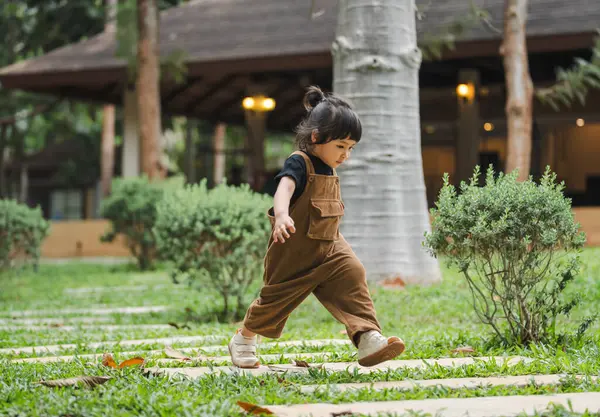 Mutlu küçük kız bahçede taş bir yolda yürüyor.