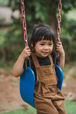 Neşeli küçük kız salıncakta oynuyor