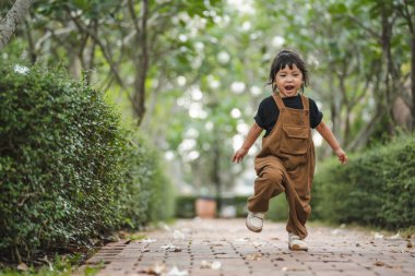 Mutlu küçük kız bahçede bir patikada koşuyor.
