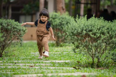 Mutlu küçük kız bahçede taş bir yolda yürüyor.