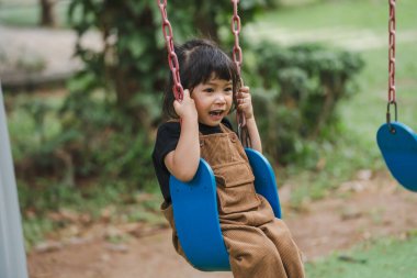 Neşeli küçük kız salıncakta oynuyor