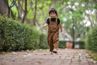Mutlu küçük kız bahçede bir patikada yürüyor.