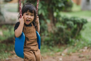Neşeli küçük kız salıncakta oynuyor