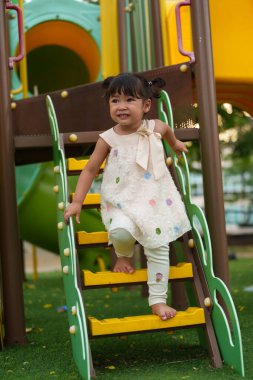 Parktaki çocuk parkında oynayan küçük mutlu kız.