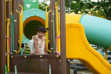 Parktaki çocuk parkında oynayan küçük mutlu kız.