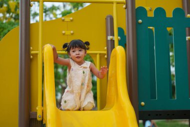 Mutlu küçük kız parktaki açık hava oyun alanında oynuyor.