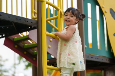 Parktaki çocuk parkında oynayan ve tırmanan mutlu kız.