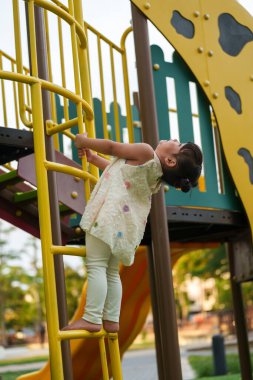 Parktaki çocuk parkında oynayan ve tırmanan mutlu kız.