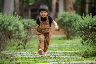 Mutlu küçük kız bahçede taş bir yolda yürüyor.