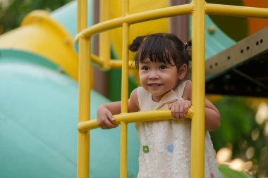 Parktaki çocuk parkında oynayan ve tırmanan mutlu kız.