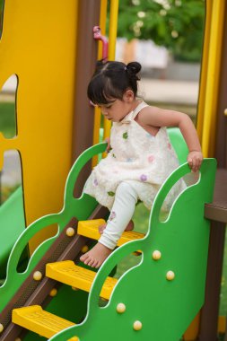 Parktaki çocuk parkında oynayan küçük mutlu kız.