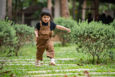 Mutlu küçük kız bahçede taş bir yolda yürüyor.