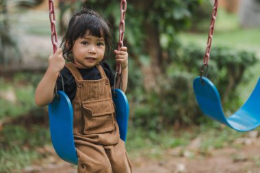 Neşeli küçük kız salıncakta oynuyor
