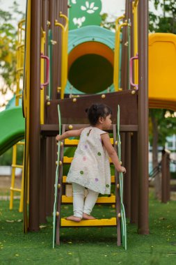 Parktaki çocuk parkında oynayan küçük mutlu kız.