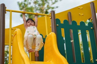 Parktaki çocuk parkında sarı barı elinden tutan mutlu küçük kız.