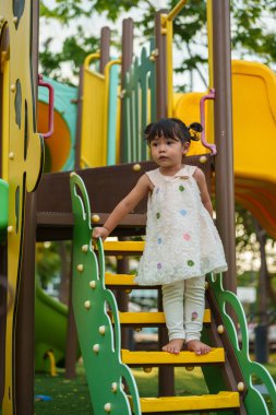 Parktaki çocuk parkında oynayan küçük mutlu kız.