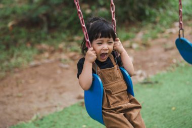 Neşeli küçük kız salıncakta oynuyor