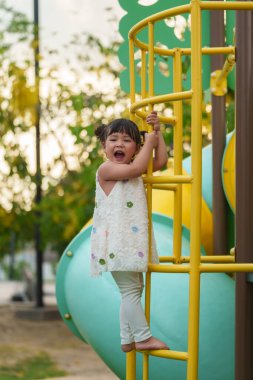 Parktaki çocuk parkında oynayan ve tırmanan mutlu kız.