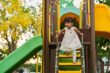 Parktaki çocuk parkında oynayan küçük mutlu kız.