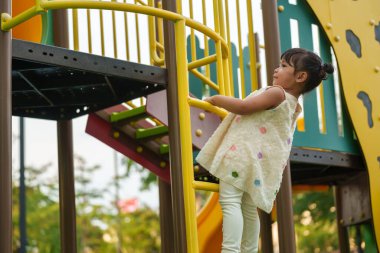 Parktaki çocuk parkında oynayan ve tırmanan mutlu kız.