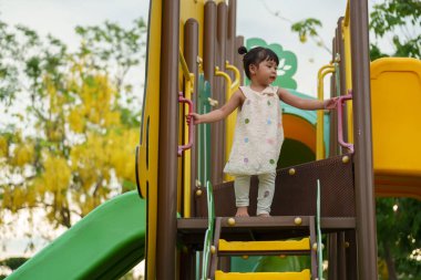 Parktaki çocuk parkında oynayan küçük mutlu kız.