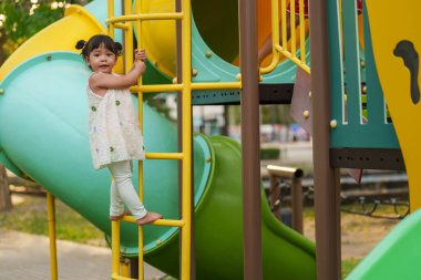 Parktaki çocuk parkında oynayan ve tırmanan mutlu kız.