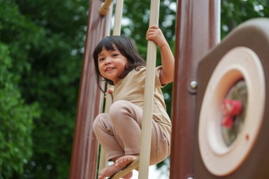 Parktaki çocuk parkında oynayan küçük mutlu kız.