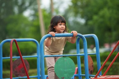 Parktaki çocuk parkında oynayan küçük mutlu kız.
