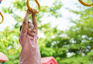 Parkta çocuk parkındaki yüzüklerde asılı duran küçük kız.
