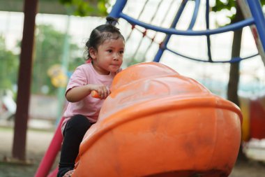 Dışarıda parkta jet ski oyuncağına binen mutlu kız.