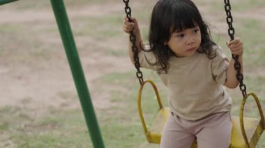 Dışarıdaki parkta salıncakta sallanan küçük kız.