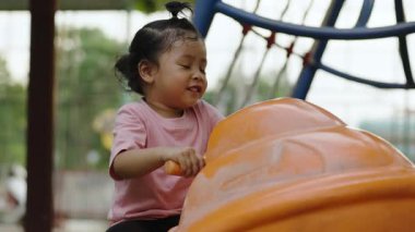 Dışarıda parkta jet ski oyuncağına binen mutlu kız.