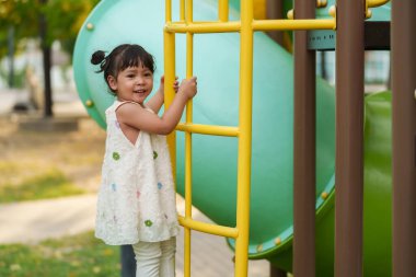 Parktaki çocuk parkında oynayan ve tırmanan mutlu kız.