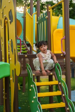 Parktaki çocuk parkında oynayan küçük mutlu kız.