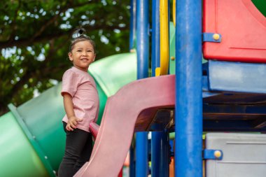 Parktaki çocuk parkında oynayan küçük mutlu kız.