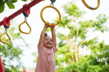 Parkta çocuk parkındaki yüzüklerde asılı duran küçük kız.