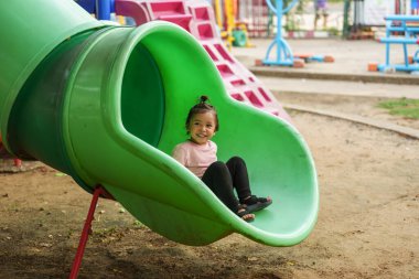 Mutlu bebek kız kayıyor ve dışarıda oyun oynuyor.