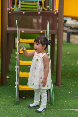 Parktaki çocuk parkında oynayan küçük mutlu kız.