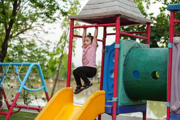 Parktaki çocuk parkında kırmızı çubuğu elinde sallayan küçük mutlu kız.