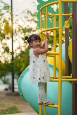 Parktaki çocuk parkında oynayan ve tırmanan mutlu kız.