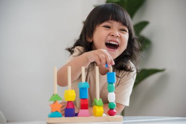 Küçük kız evde eğitici tahta oyuncaklarla oynuyor.