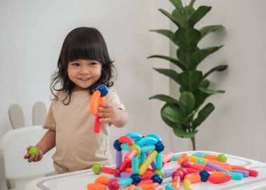 Küçük kız evde renkli manyetik inşaat oyuncağı oynuyor.