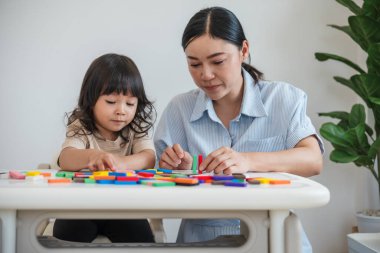 Küçük kız ve annesi renkli tahta blok oyuncakları ya da domino oyunu oynuyorlar.