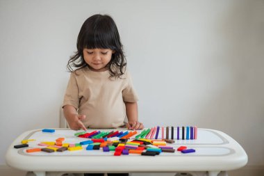 Küçük kız renkli tahta blok oyuncağı ya da domino oyunu oynuyor.