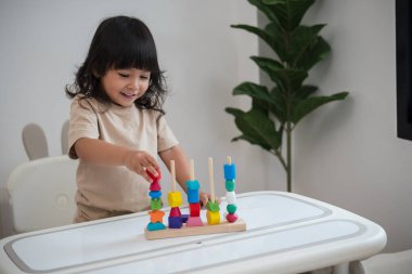 Küçük kız evde eğitici tahta oyuncaklarla oynuyor.