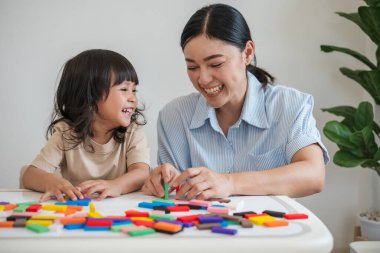 Küçük kız ve annesi renkli tahta blok oyuncakları ya da domino oyunu oynuyorlar.