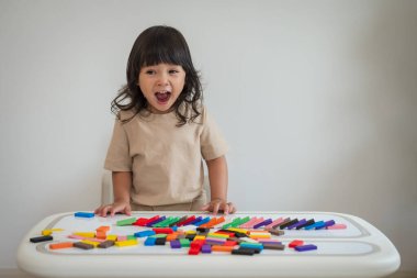 Küçük kız renkli tahta blok oyuncağı ya da domino oyunu oynuyor.