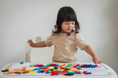 Küçük kız renkli tahta blok oyuncağı ya da domino oyunu oynuyor.