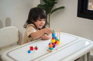 Küçük kız evde eğitici tahta oyuncaklarla oynuyor.