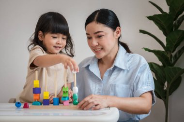 Küçük kız ve annesi evde eğitici tahta oyuncaklarla oynuyorlar.